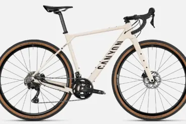 Seitenansicht eines Canyon Grizl 7 Gravelbikes in heller Sandfarbe mit schwarzen Akzenten, ausgestattet mit Schwalbe G-One Reifen und DT Swiss Laufrädern.