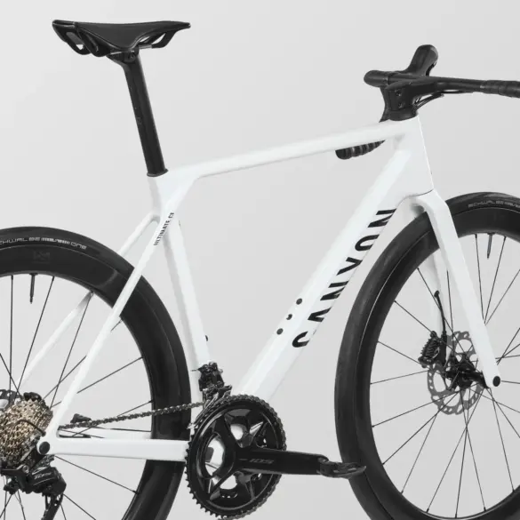 Detailansicht eines weißen Canyon Ultimate CF 7 A.50 Rennrads, Fokus auf den Carbonrahmen, die Kurbelgarnitur und das Hinterrad.