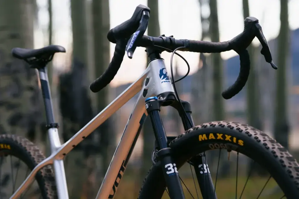 Nahaufnahme des silbernen Pivot LES SL Drop Bar Fahrradrahmens mit Dropbar-Lenker, breiter Maxxis-Reifen und FOX Gabel.