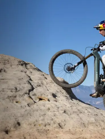 Mountainbiker fährt das Specialized Turbo Levo R Expert auf einem felsigen Hang mit blauem Himmel.