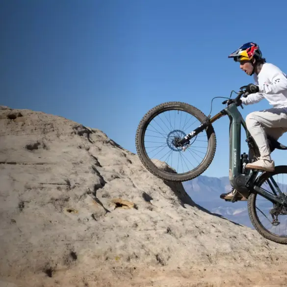 Mountainbiker fährt das Specialized Turbo Levo R Expert auf einem felsigen Hang mit blauem Himmel.