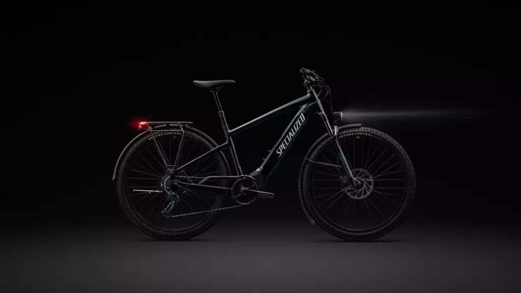 Studioaufnahme eines schwarzen Specialized Turbo Tero 5.0 EQ E-Bikes mit Beleuchtung und Gepäckträger auf schwarzem Hintergrund.