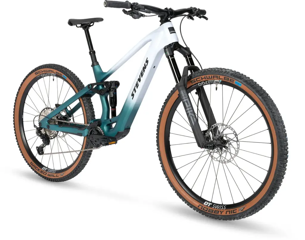 Vorderansicht eines weißen und türkisfarbenen Stevens E-Maverick AM 7.4.3 E-Mountainbikes mit braunen Reifen und silberner Kette, auf weißem Hintergrund.