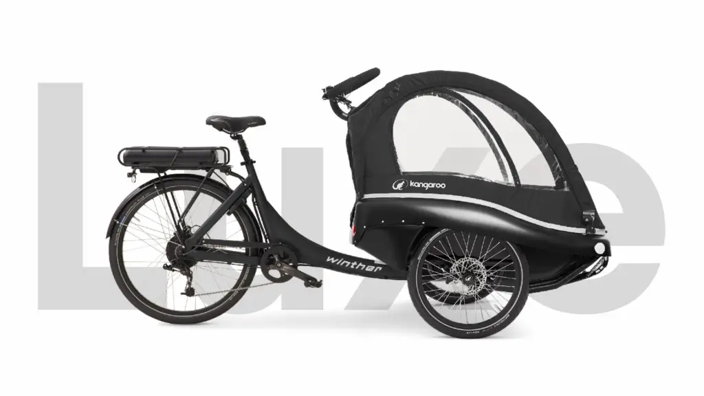 Kangaroo Luxe Lastenrad, ein schwarzes Elektro-Dreirad mit geschlossener Transportkabine für Kinder und Gepäck, mit Gepäckträger und Batterie.