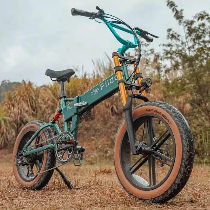 Grünes, faltbares Fiido M1 Pro Fatbike mit breiten Reifen und auffälligem Lenker in einer natürlichen Umgebung.