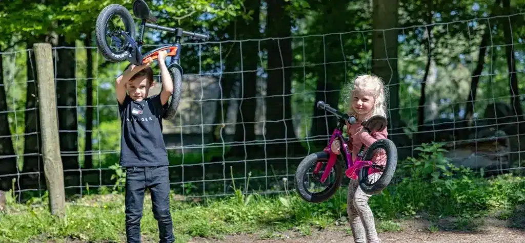 Junge und Mädchen halten jeweils ein Motobécane Roadie Laufrad