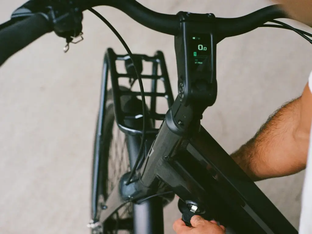 Detailansicht des Lenkers eines schwarzen eBikes mit einem integrierten digitalen Display, das Geschwindigkeit und Akkuladestand anzeigt.