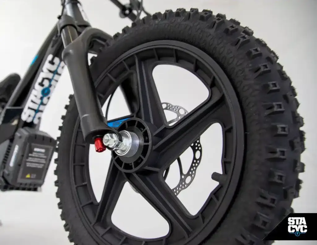 Vorderrad mit grobstolliger Bereifung und hydraulischer Scheibenbremse sowie die einstellbare Luftfedergabel eines STACYC Elektro-Balancebikes.