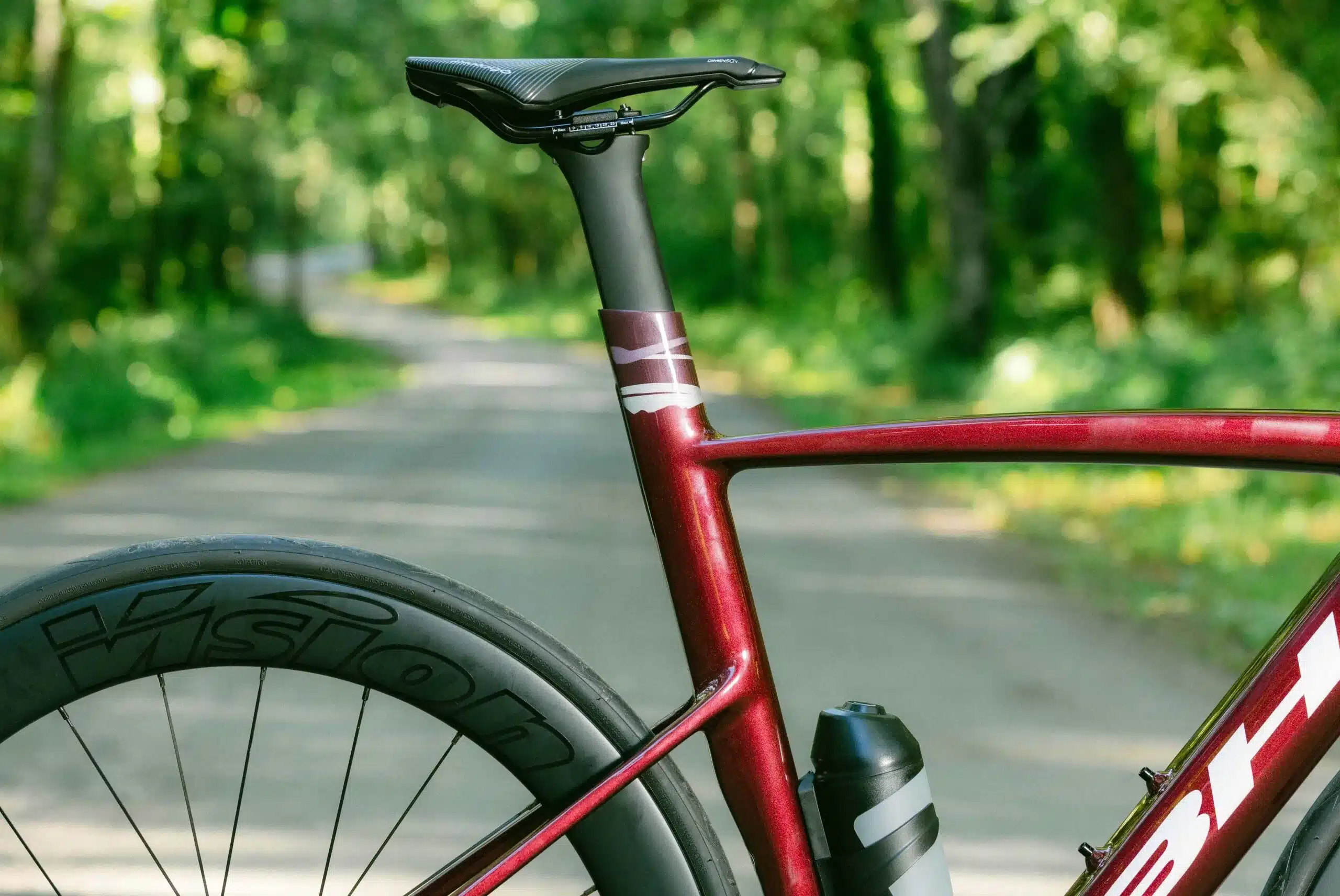 Nahaufnahme des Rahmens und der Sattelstütze eines roten BH iAEROLIGHT E-Rennrads auf einer Waldstraße