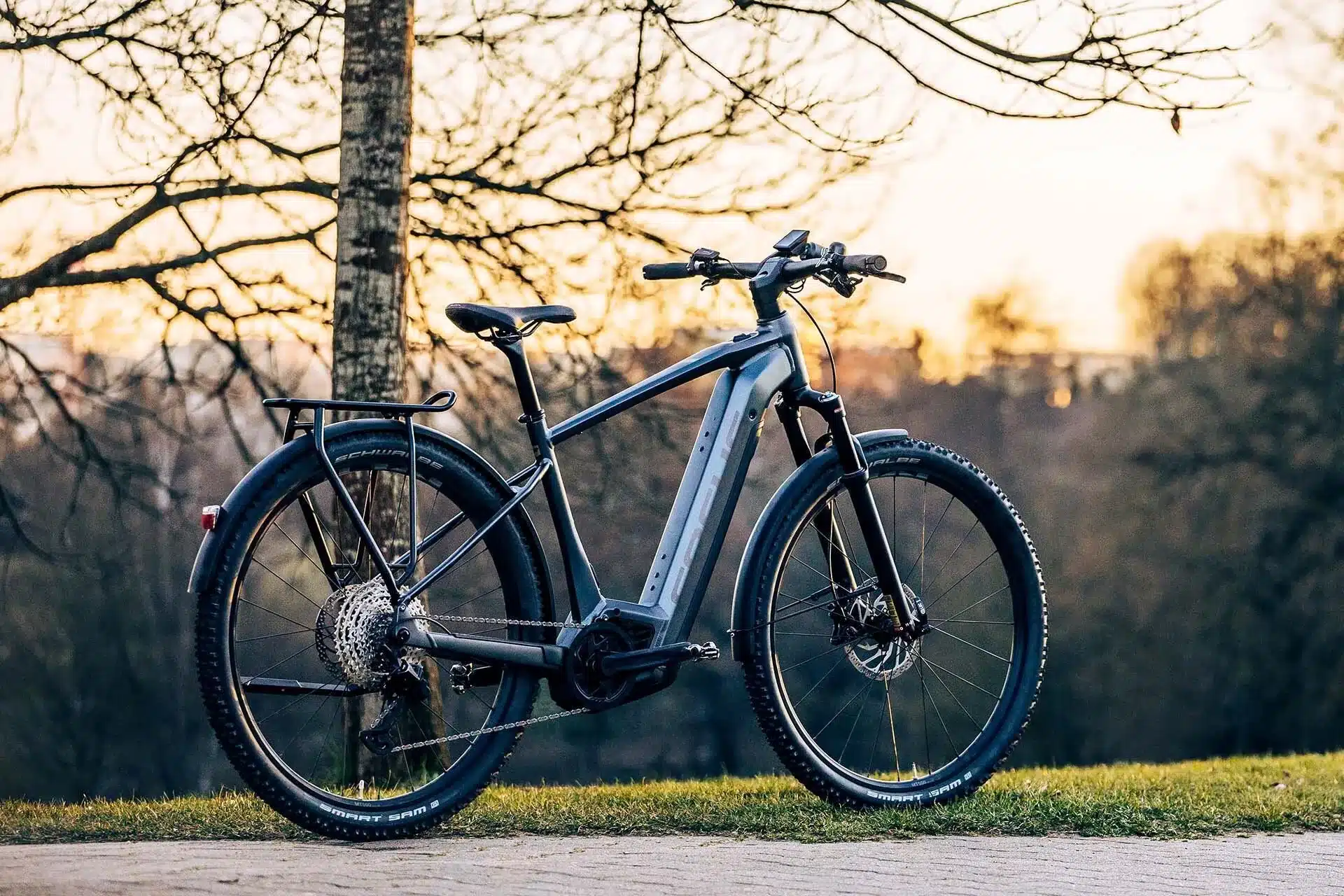 Focus Aventura² 6.9 E-Trekkingbike mit Gepäckträger und breiten Reifen, abgestellt im Freien bei Sonnenuntergang
