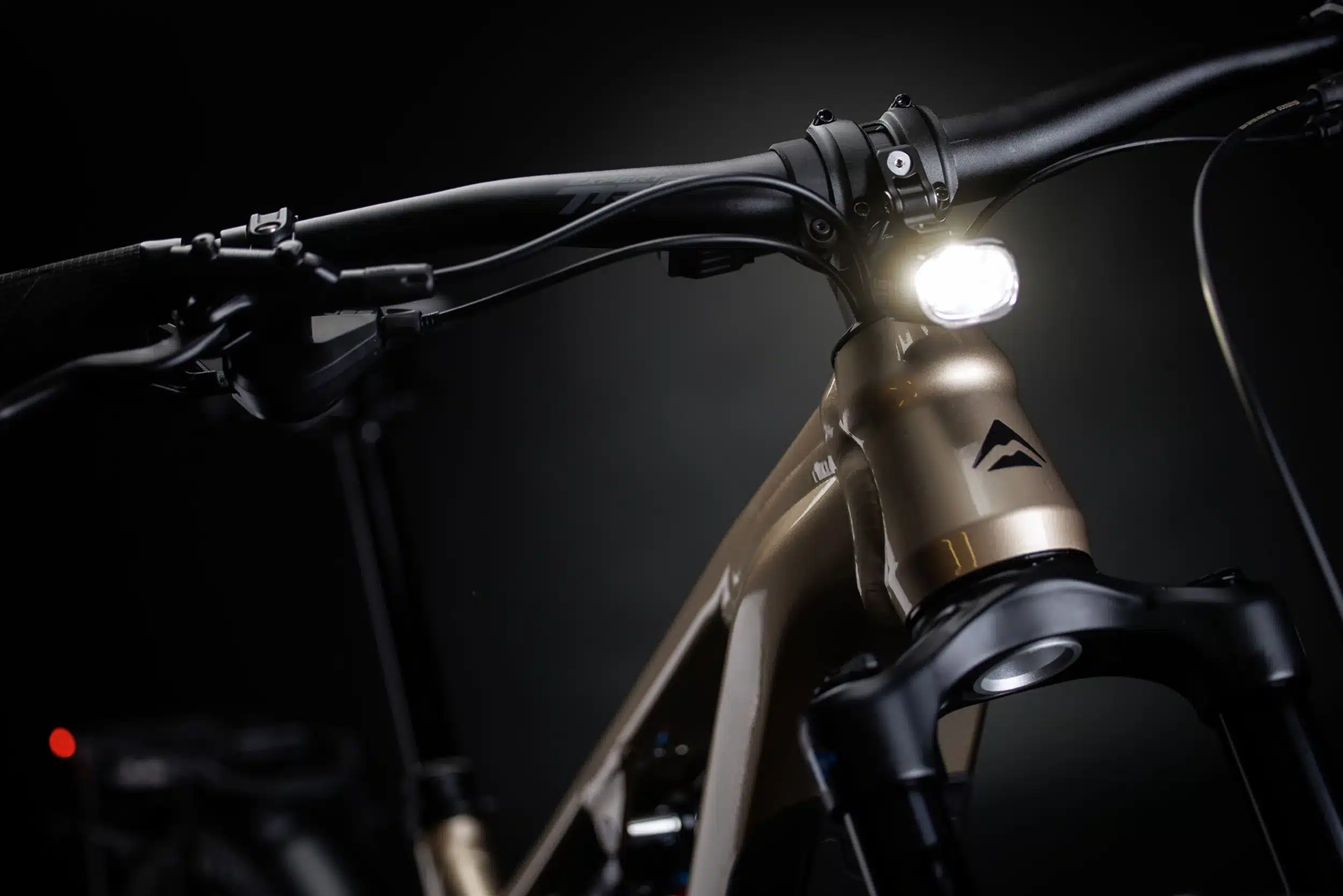 Nahaufnahme des Lenkers und Frontlichts am Merida eONE-FORTY 475 EQ E-Bike vor dunklem Hintergrund.