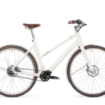Schindelhauer Antonia E-Bike in Sahneweiß mit braunem Ledersattel und Ledergriffen, seitliche Ansicht