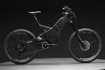 Seitenansicht eines "2024 Revolution" Downhill E-Bikes von Hi-Power Cycles mit auffälliger Carbon-Optik am Rahmen, breiten Reifen und Federung.