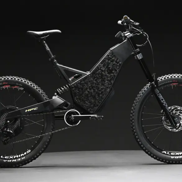 Seitenansicht eines "2024 Revolution" Downhill E-Bikes von Hi-Power Cycles mit auffälliger Carbon-Optik am Rahmen, breiten Reifen und Federung.