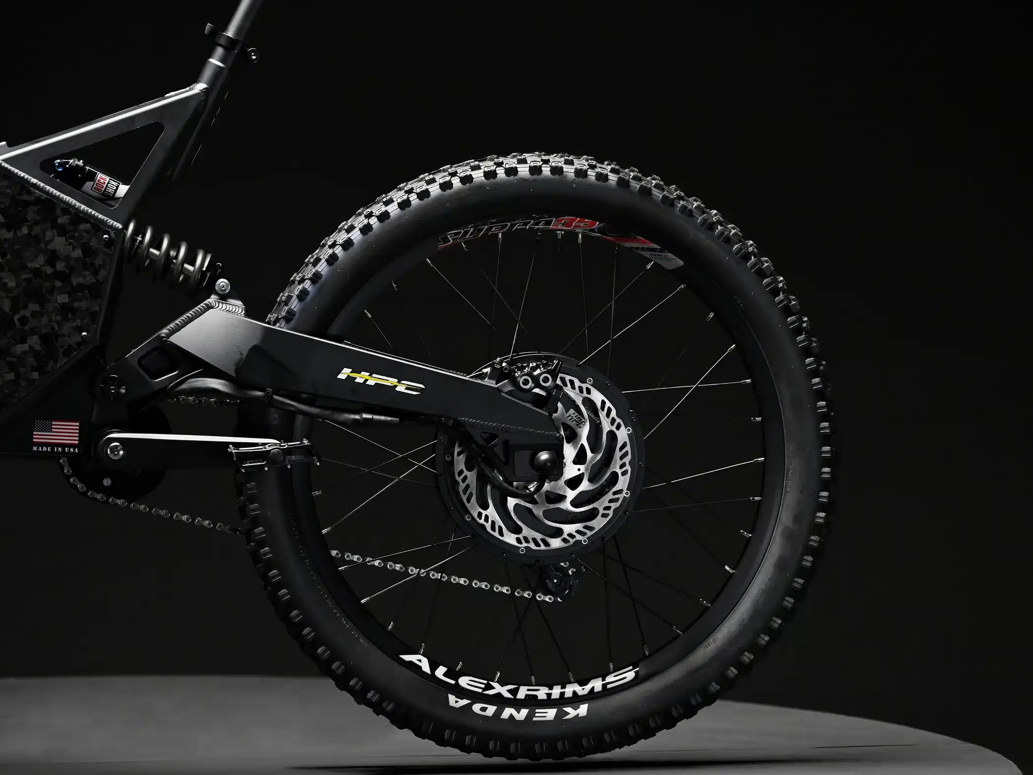 Detailaufnahme des Hinterrads eines Hi-Power Cycles 2024 Revolution E-Bikes, mit Fokus auf den Kenda Reifen, die Alexrims Felge, die Scheibenbremse und den integrierten Nabenmotor.