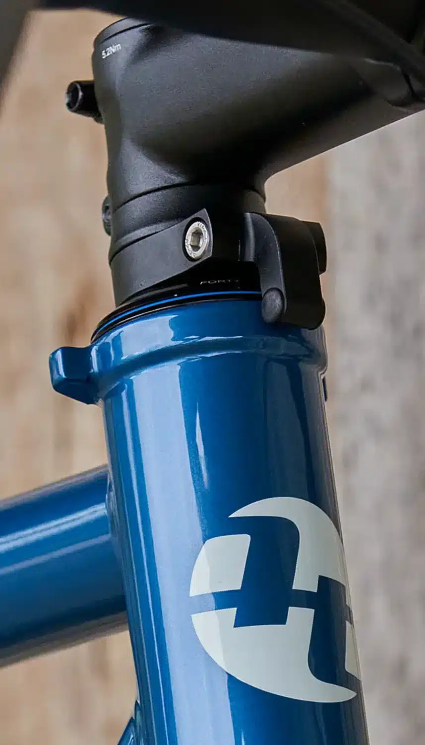 Nahaufnahme des Steuerrohrs eines blauen Trekkingrads mit dem silbernen Tout Terrain Logo. Der Vorbau und die Ahead-Kappe sind sichtbar.