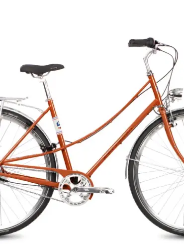 Ein Böttcher Ditmarsia Swing Fahrrad in der auffälligen Farbe Perlorange, mit elegant geschwungenem Stahlrahmen, Gepäckträger und Retro-LED-Scheinwerfer, isoliert auf weißem Hintergrund.