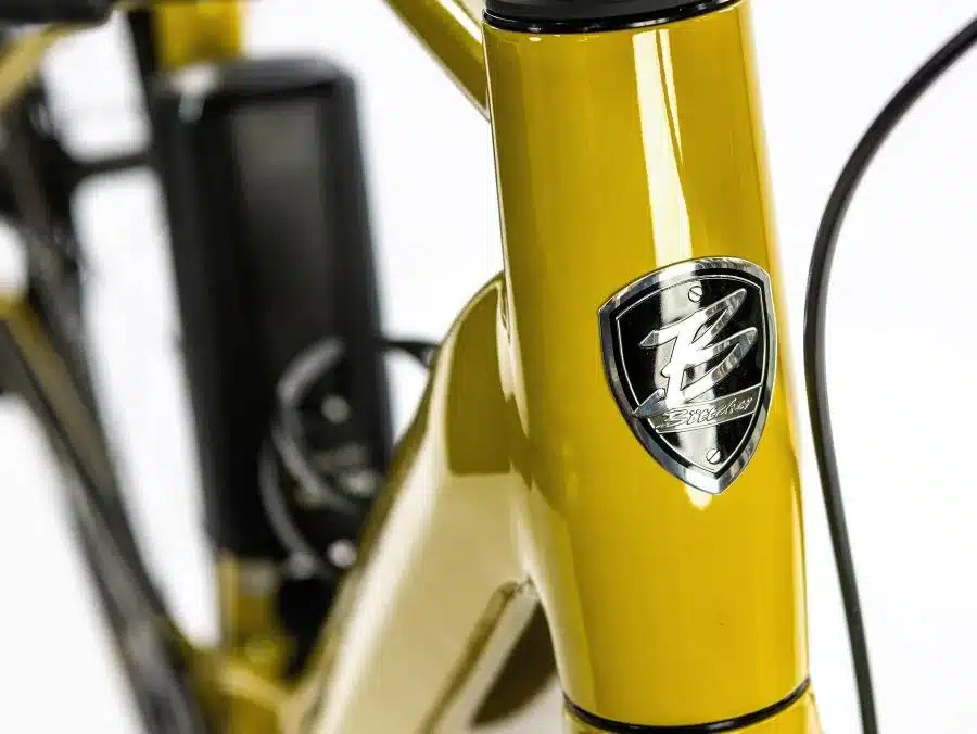 Detailansicht des gelben Böttcher Gravel-E SX Fahrradrahmens mit silbernem Böttcher-Logo und schwarzem Akku.