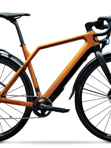 Detailaufnahme eines orangefarbenen Cyklaer Base E-Gravelbikes mit Carbonrahmen, Schutzblechen und Gepäckträger, freigestellt vor weißem Hintergrund.