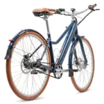 Dunkelblaues E-Bike mit braunem Sattel und Griffen, breiten Reifen und Riemenantrieb, auf weißem Hintergrund.