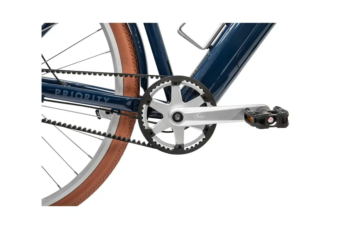 Nahaufnahme der wartungsarmen Gates Carbon Drive Riemenantriebs und der silbernen Pedale eines Priority Glide E-Bikes mit braunen Reifen.