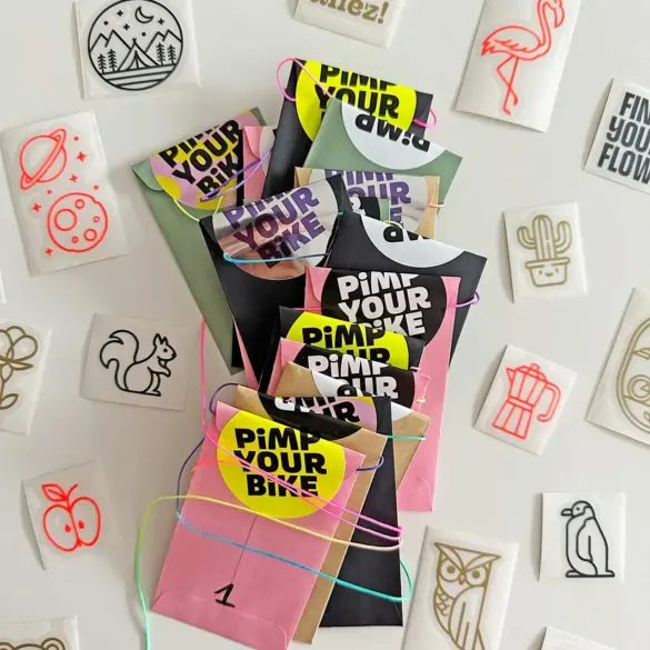 Adventskalender für Radfahrer mit bunten, einzeln verpackten Stickern aus Vinylfolie, umgeben von verschiedenen Motivstickern