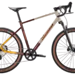 Ein hellbeiges und rot-gelb verlaufendes Diamant 140 Gravelbike mit braunen Reifen und schwarzer Federgabel.