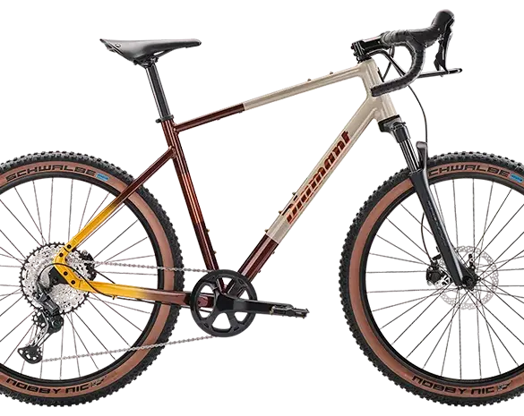 Ein hellbeiges und rot-gelb verlaufendes Diamant 140 Gravelbike mit braunen Reifen und schwarzer Federgabel.