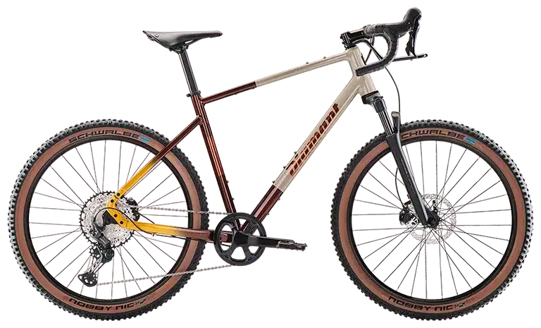 Ein hellbeiges und rot-gelb verlaufendes Diamant 140 Gravelbike mit braunen Reifen und schwarzer Federgabel.