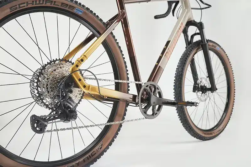 Detailaufnahme des Diamant 140 Fahrrads mit Fokus auf das Shimano GRX Schaltwerk, die breite Kassette, die Schwalbe Nobby Nic Reifen und die SR Suntour Federgabel.