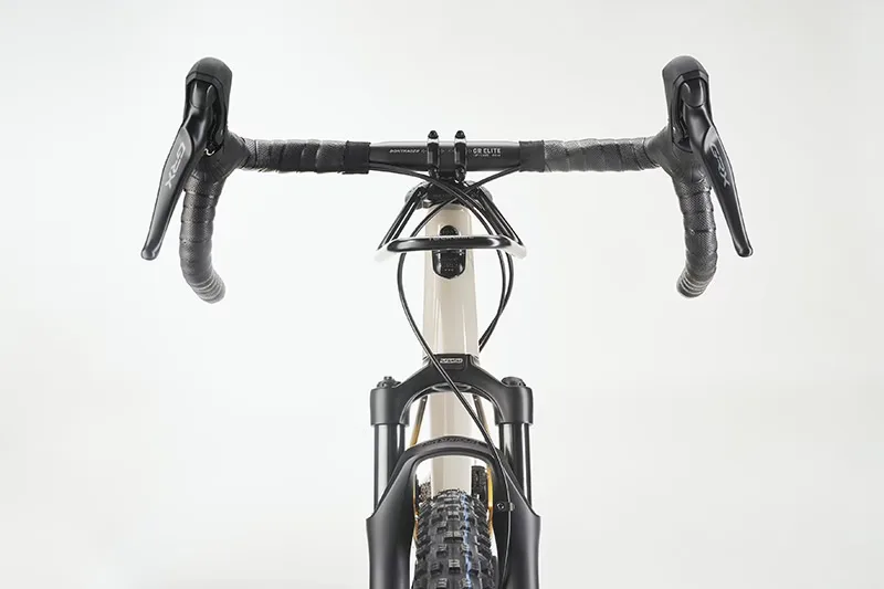 Vorderansicht eines cremefarbenen Diamant 140 Gravelbikes mit schwarzem Lenkerband, Shimano GRX-Schalthebeln und schwarzer Federgabel.