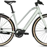 Das FLYER Upstreet SL 3.63 Trapez E-Bike in seitlicher Ansicht mit hellem Rahmen, Riemenantrieb, Schutzblechen und Gepäckträger