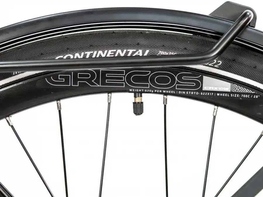 Detailansicht des Hinterrads eines Grecos Eli Urban Singlespeed Fahrrads mit schwarzem Continental Reifen und GRECOS Schriftzug auf der Felge, sowie Schutzblech und Gepäckträgerbügel.