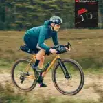 Fahrerin auf dem GX-1200 1st Edition Gravelbike der vsf fahrradmanufaktur mit Dirty-Mustard-Lackierung, unterwegs auf einem Schotterweg