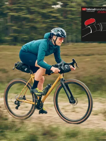 Fahrerin auf dem GX-1200 1st Edition Gravelbike der vsf fahrradmanufaktur mit Dirty-Mustard-Lackierung, unterwegs auf einem Schotterweg