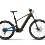 Seitenansicht eines HAIBIKE ALLTRAIL 6 E-Mountainbikes mit braunem Hauptrahmen und blauem Hinterbau, ausgestattet mit RockShox-Federung und Schwalbe Nobby Nic Reifen