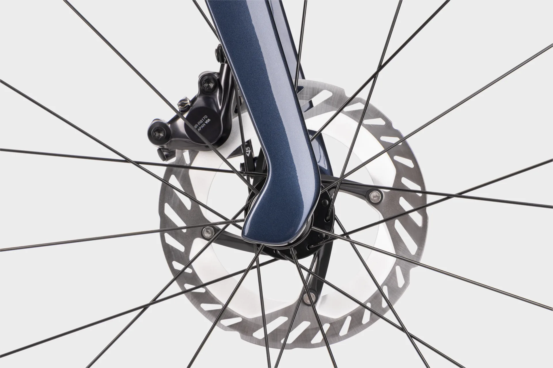 Detailaufnahme des Vorderrads eines dunkelblauen Simplon Kiaro Rennrads, Fokus auf die hydraulische Scheibenbremse und die Carbongabel.