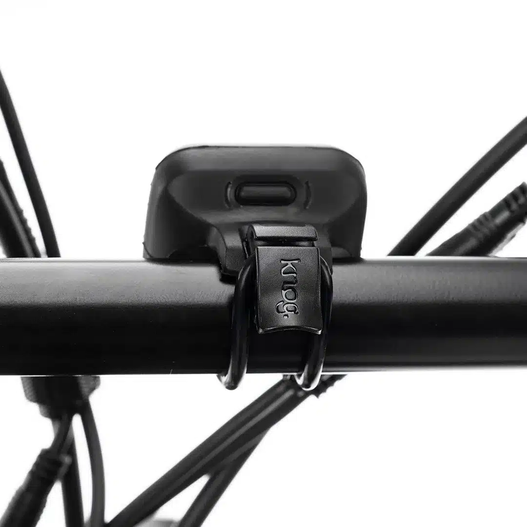 Knog Blinder Grid Fahrradlicht mit Logo auf dem Befestigungsband, montiert an einem schwarzen Fahrradlenker.