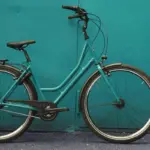 Türkisfarbenes Hollandrad im Profil vor tealblauer Wand