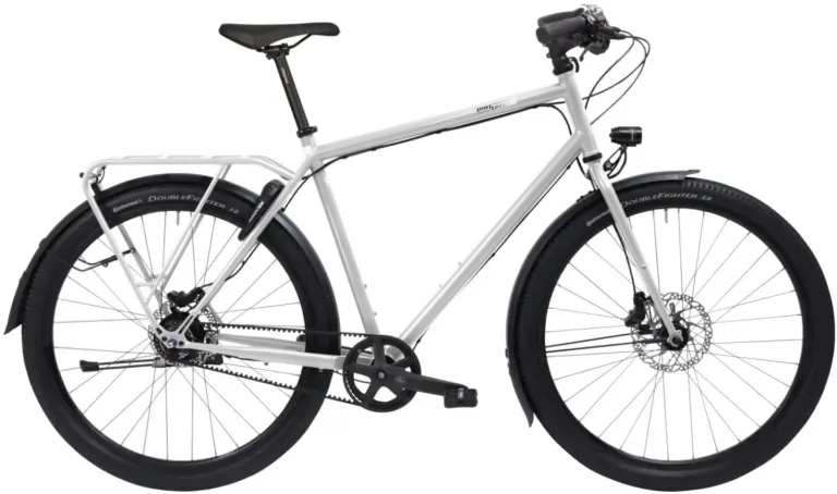 Ein schwarzes Tout Terrain Metropolitan Fahrrad mit Gepäckträger und Schutzblechen, das für den Einsatz auf Straßen und Schotterwegen konzipiert ist.