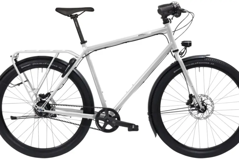 Ein schwarzes Tout Terrain Metropolitan Fahrrad mit Gepäckträger und Schutzblechen, das für den Einsatz auf Straßen und Schotterwegen konzipiert ist.