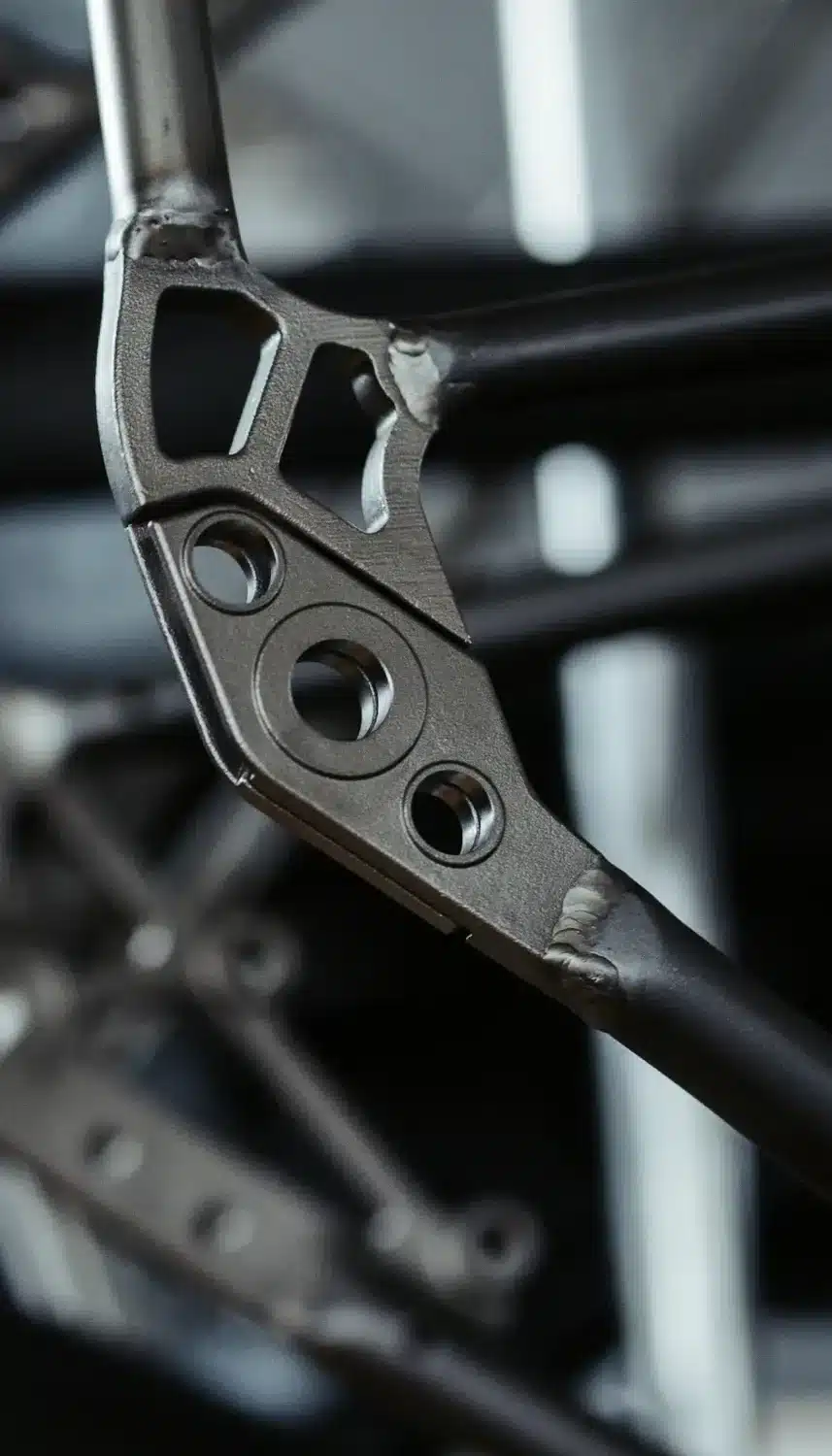 Detail des Fahrradrahmens aus Stahl mit Schweißnähten und mehreren runden Löchern zur Befestigung.