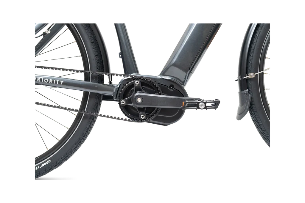 Nahaufnahme des Mittelmotors, des Tretkurbelgehäuses und des Gates Carbon Drive Riemens eines grauen Priority Current Plus E-Bikes.