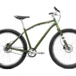 Grünes Priority Sauce Offroad-Cruiser Fahrrad, frontal leicht von links im Studio aufgenommen, mit breiten Reifen und Riemenantrieb.