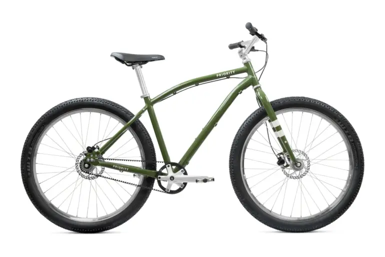 Grünes Priority Sauce Offroad-Cruiser Fahrrad, frontal leicht von links im Studio aufgenommen, mit breiten Reifen und Riemenantrieb.