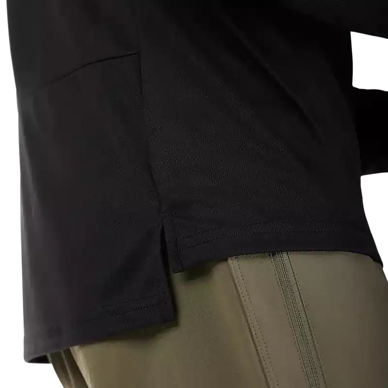 Nahaufnahme des unteren Bereichs eines schwarzen Langarmtrikots aus Mesh-Gewebe über einer olivfarbenen Hose