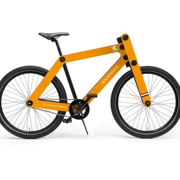 Ein oranges Sandwichbike WF1-S mit Holzrahmen und schwarzen Rädern steht auf weißem Hintergrund. Das Fahrrad hat eine auffällige orangefarbene Rahmenkonstruktion aus Holz und ist mit schwarzen Reifen und Felgen ausgestattet. Auf dem Oberrohr ist ein stilisiertes weißes Logo und der Schriftzug "@NLinPanama" angebracht, während am Rahmenende das "Sandwichbikes"-Logo zu sehen ist. Kleine farbige Streifen in Rot, Weiß und Blau zieren die Gabel.
