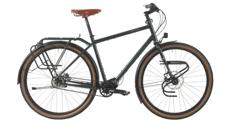 Dunkelgrünes Tout Terrain Tourenrad Silkroad mit braunem Ledersattel, Gepäckträgern vorne und hinten sowie einem Pinion-Mittendrive-Getriebe.