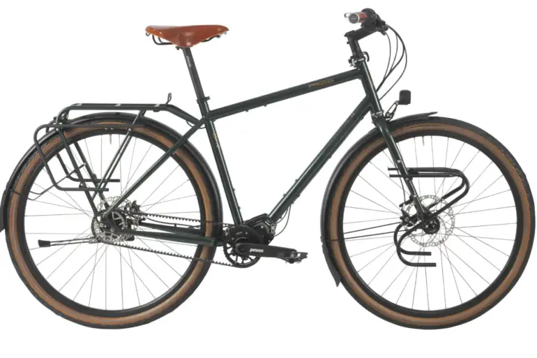 Dunkelgrünes Tout Terrain Tourenrad Silkroad mit braunem Ledersattel, Gepäckträgern vorne und hinten sowie einem Pinion-Mittendrive-Getriebe.