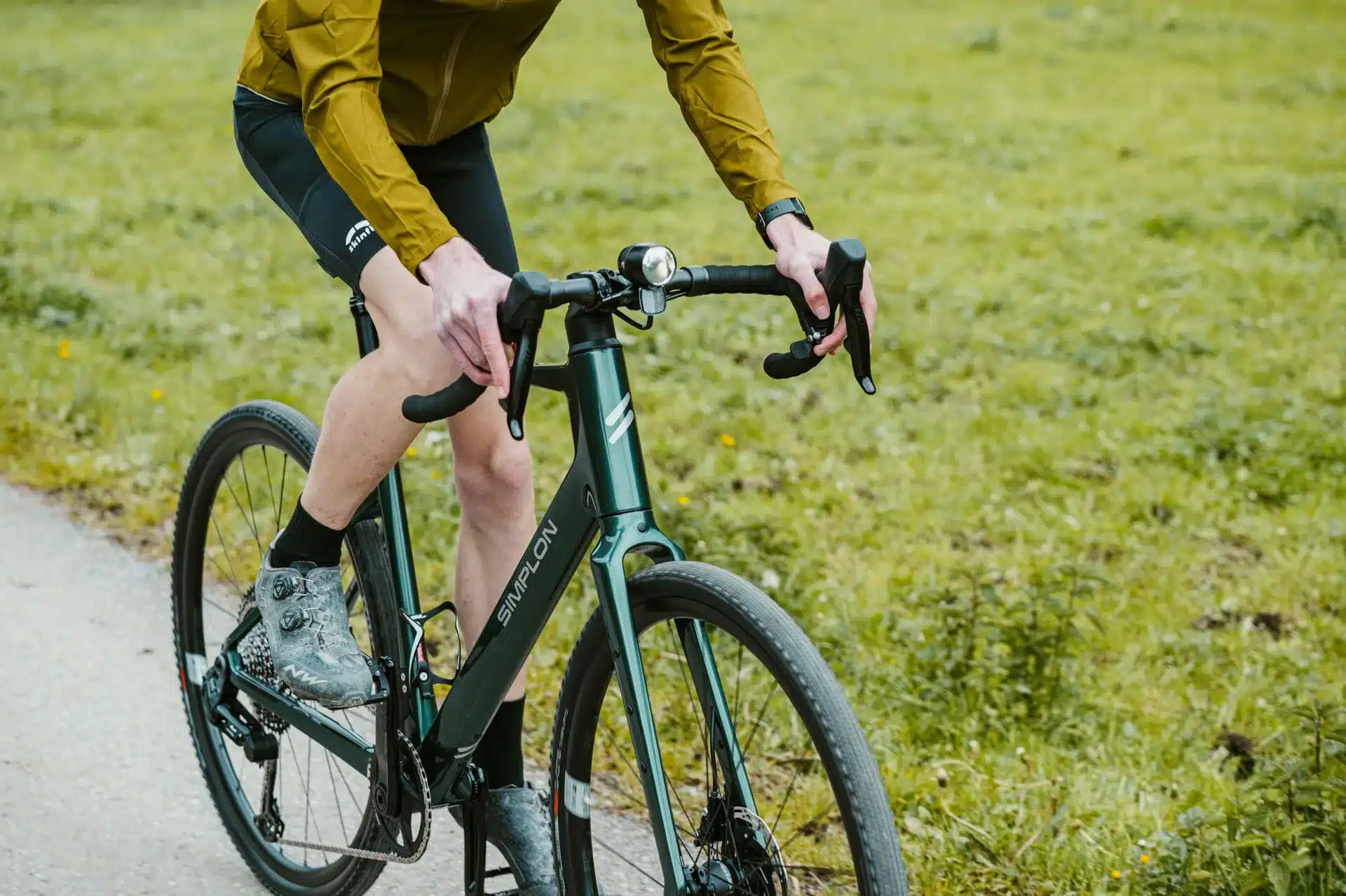Grünes SIMPLON GRID :eLight E-Gravelbike von vorne mit einem Fahrer auf einem Feldweg
